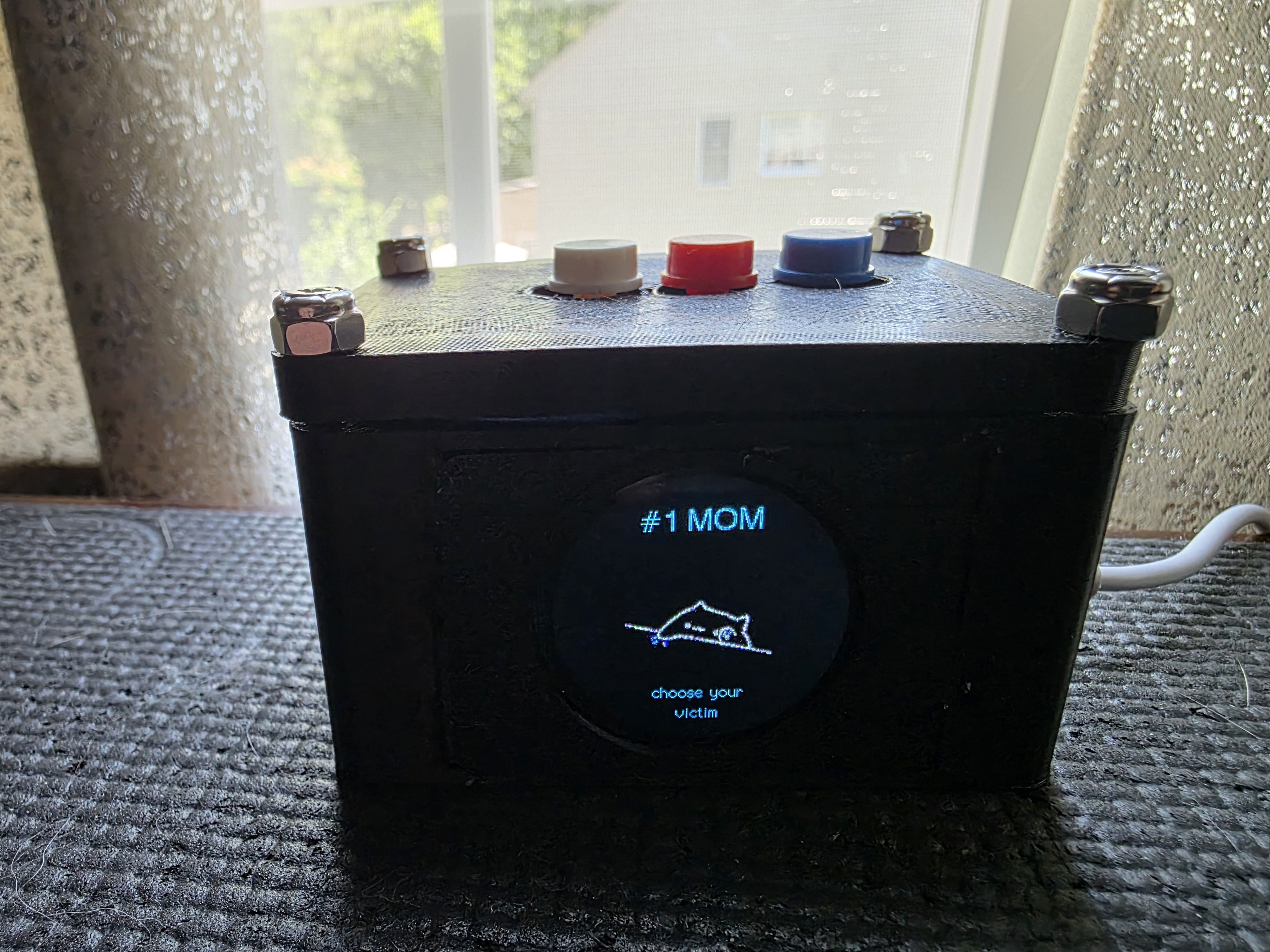 Small button box with a round display reading number one mom, choose your victim